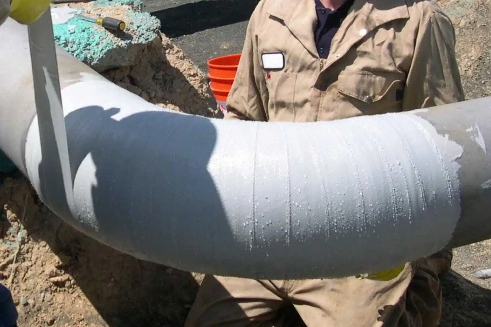 A technician applying a composite wrap system to a pipeline