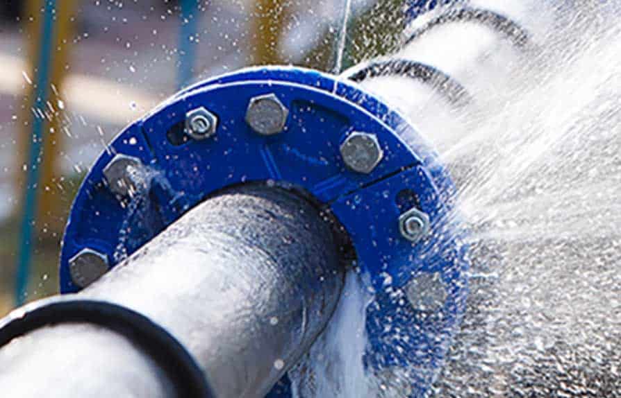 A close-up of a leaking pipe joint in an industrial setting