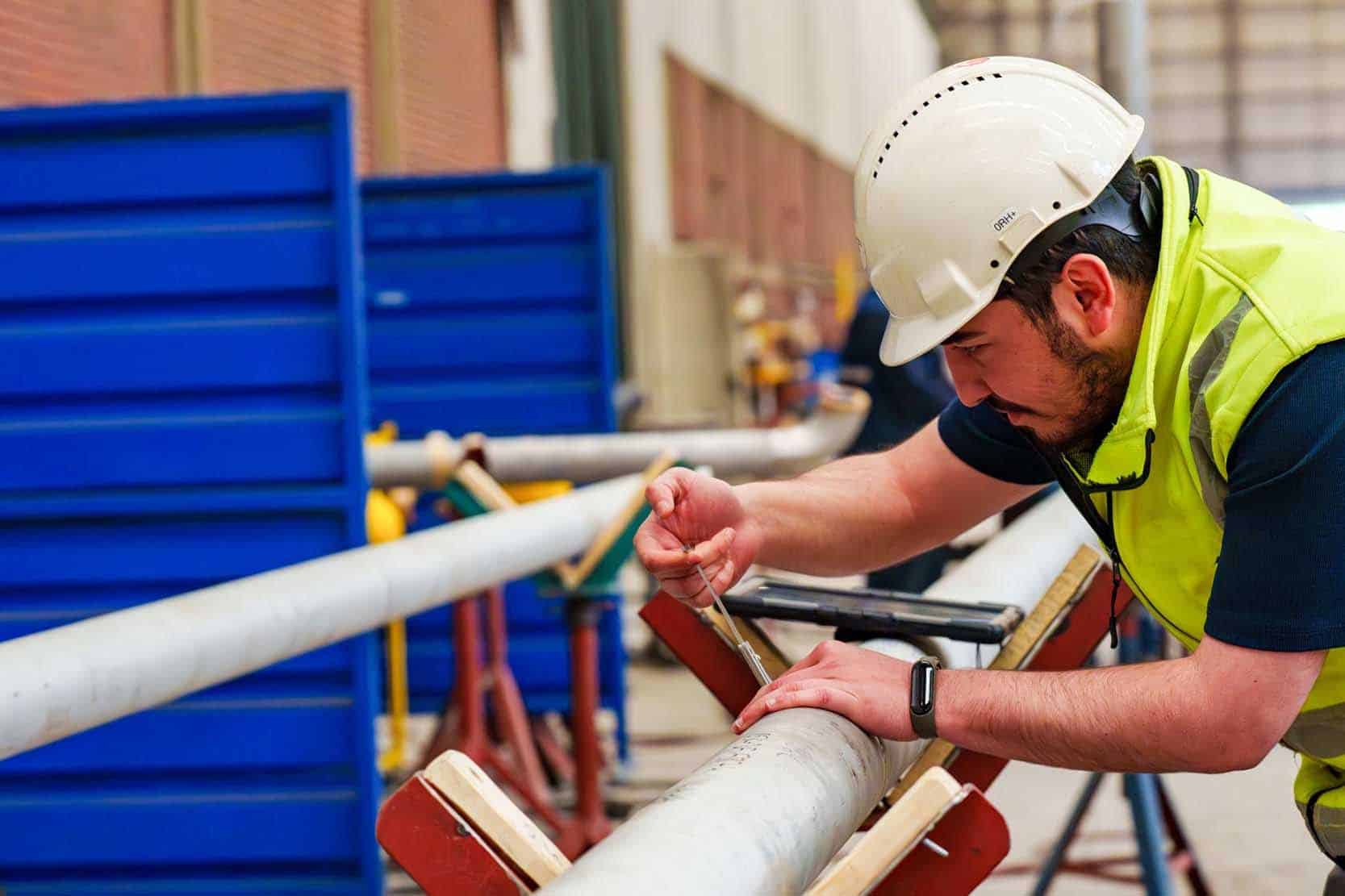 A person using calipers to measure the outer diameter of a large pipe