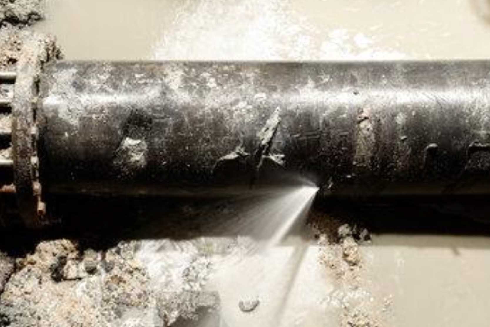 Close-up of a small pinhole leak on a metal pipe