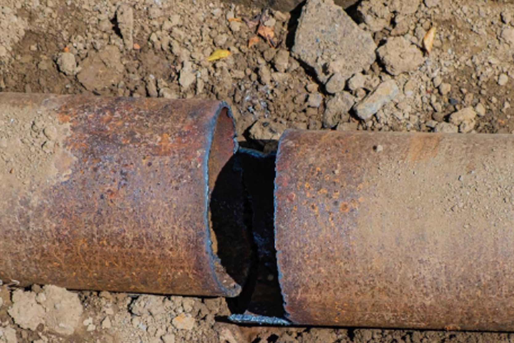 A severely corroded and broken pipe that is beyond repair with a clamp